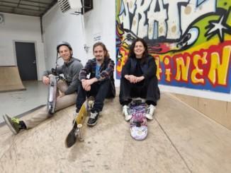 tre unga vuxna sitter i en skejthall