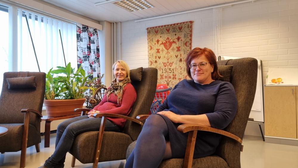 två kvinnor sitter i ett vardagsrumsliknande rum