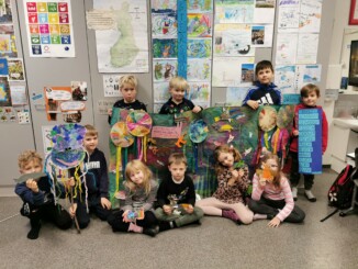 Tio barn i skola som visar upp djur och en bakgrund de gjort.