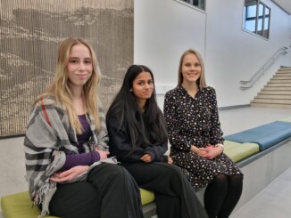 Tre kvinnor sitter på en bänk i en skola.